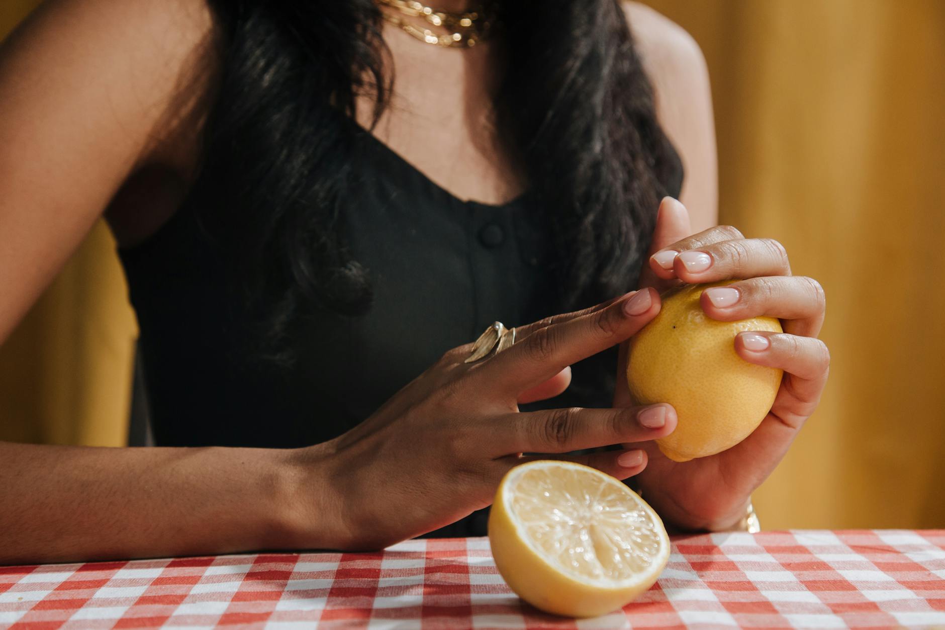 A hand holding an orange vibrator against a minimalistic purple backdrop