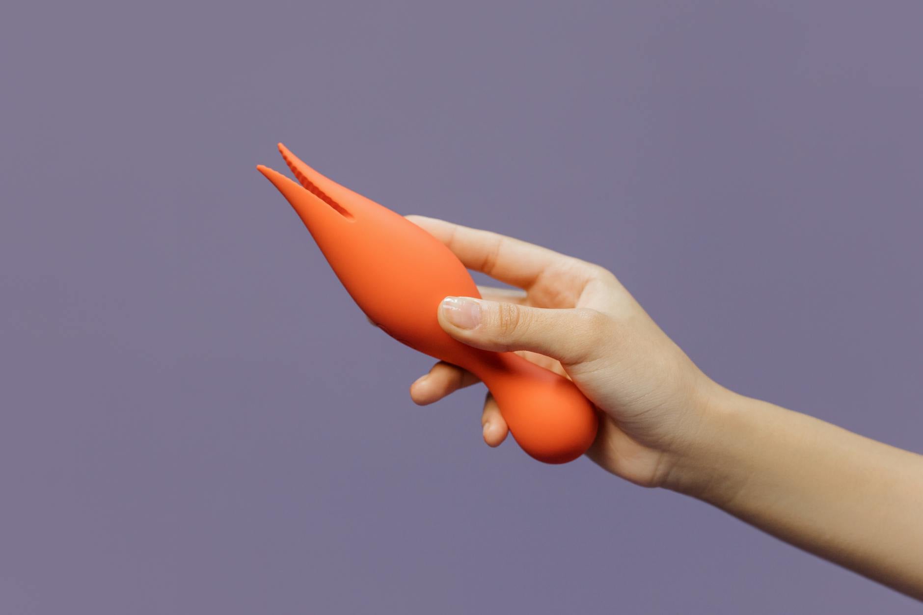 A hand holding a vibrator against a minimalistic backdrop, symbolizing modern intimate exploration between partners.