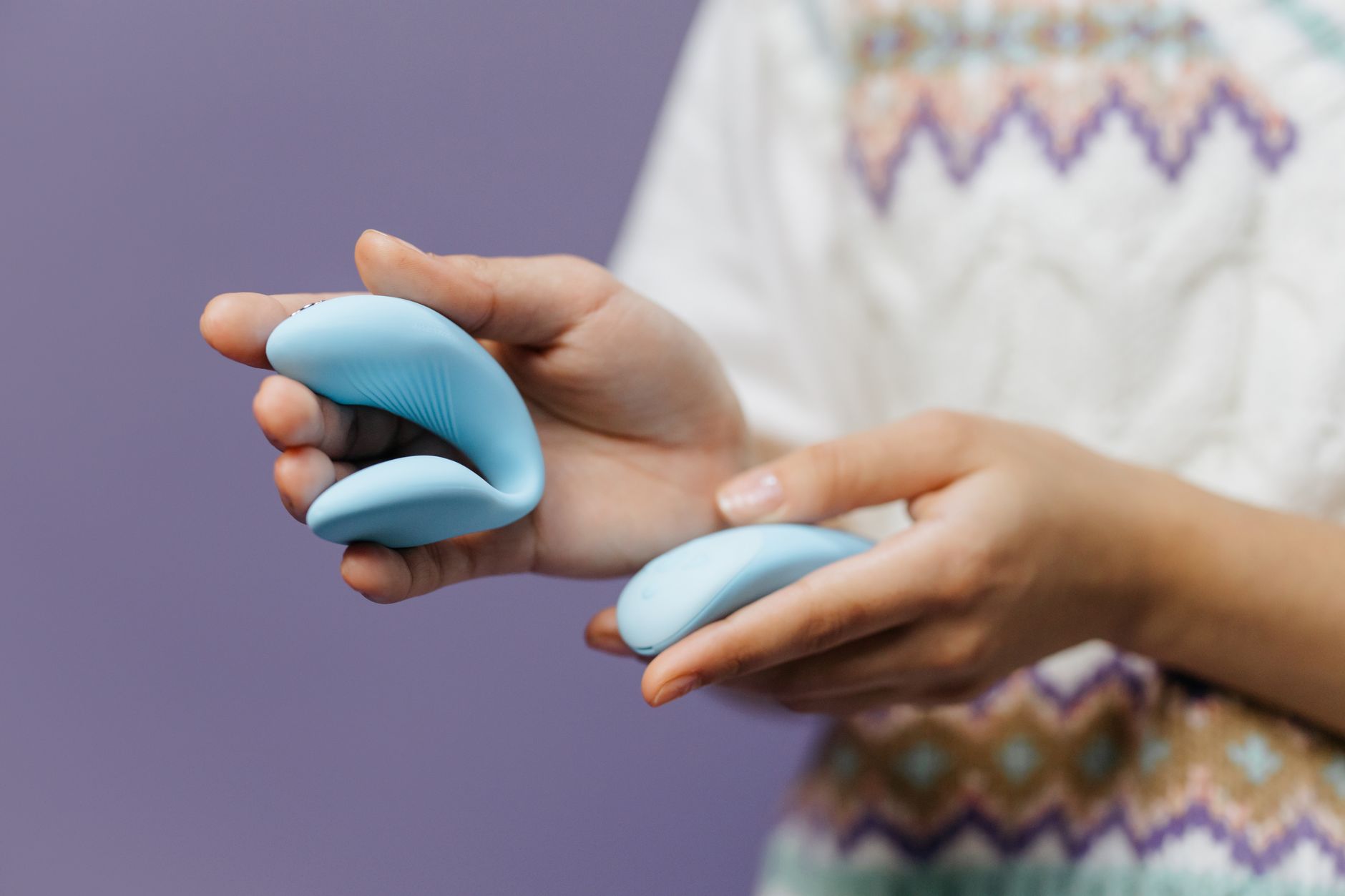 Um casal jovem de mãos dadas segurando um vibrador azul, representando intimidade e modernidade no relacionamento