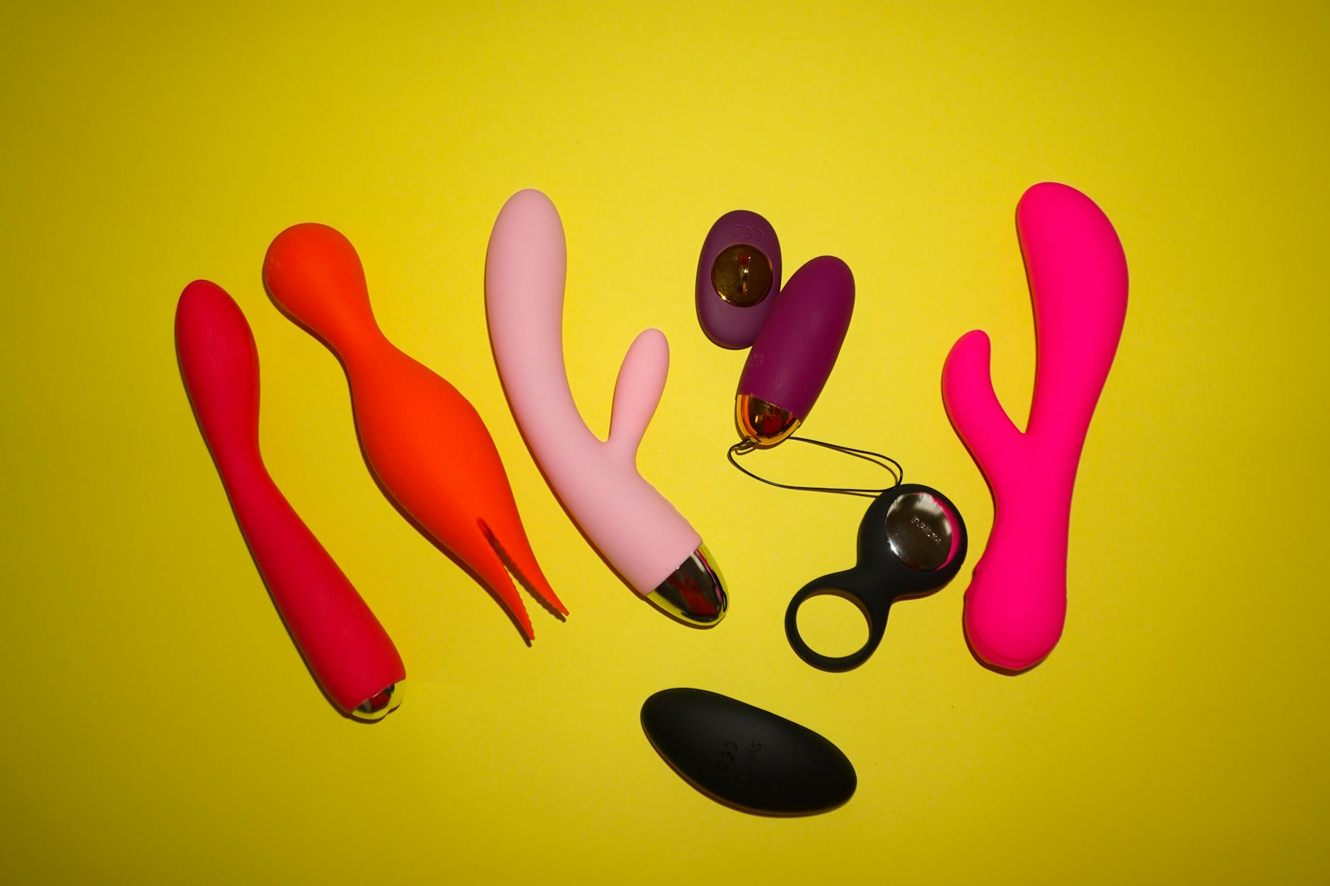 Pink vibrator on a purple background with heart confetti and candles for a romantic vibe